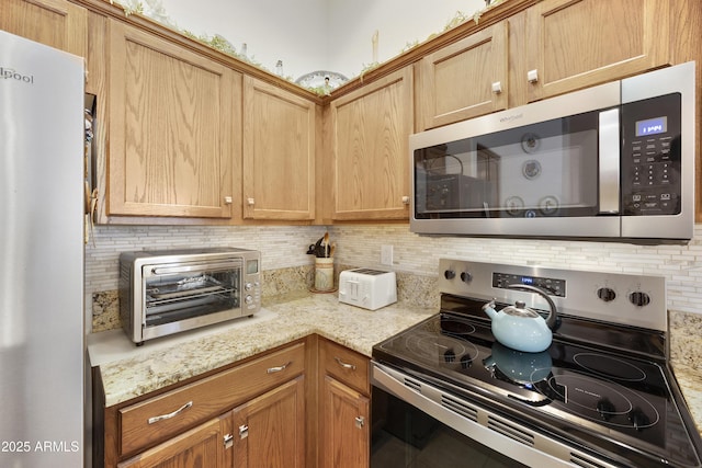 kitchen featuring appliances with stainless steel finishes, decorative backsplash, and light stone counters