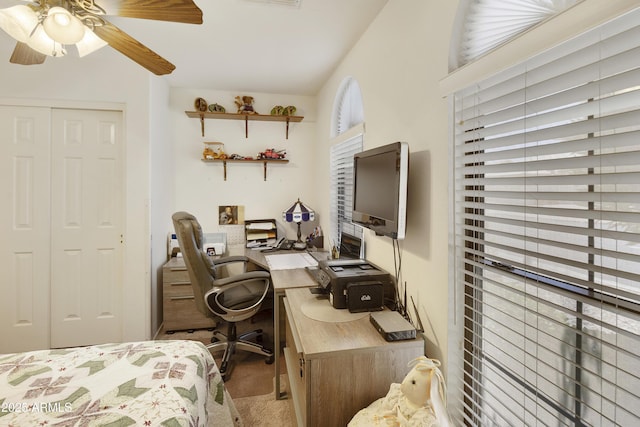 carpeted bedroom with a closet, vaulted ceiling, an office area, and a ceiling fan