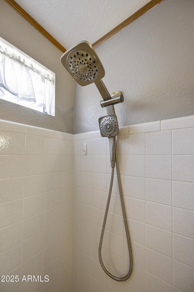 bathroom view of tiled shower, a textured ceiling, and a textured wall