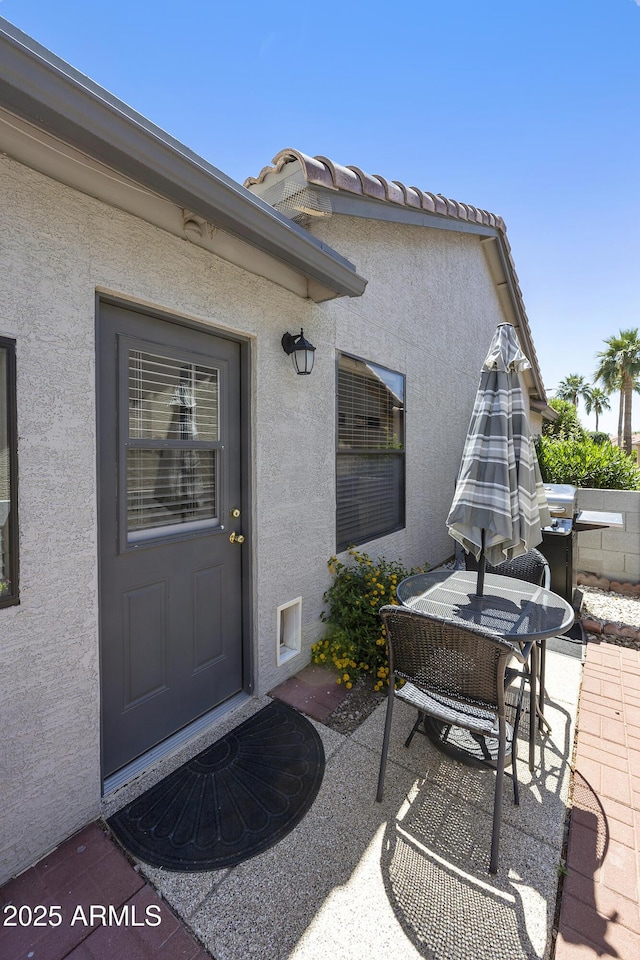 doorway to property with stucco siding, a patio, and outdoor dining space