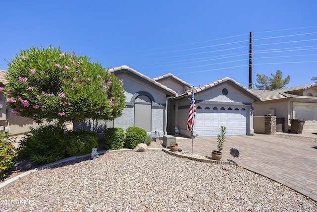 view of front of property with a garage, driveway, a tile roof, and stucco siding