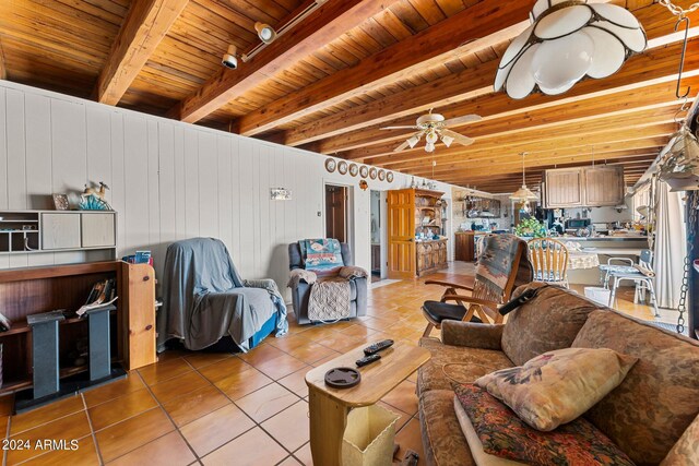 living room with wood ceiling, tile patterned flooring, wood walls, beam ceiling, and ceiling fan