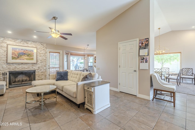 living room with lofted ceiling, plenty of natural light, a fireplace, and ceiling fan with notable chandelier