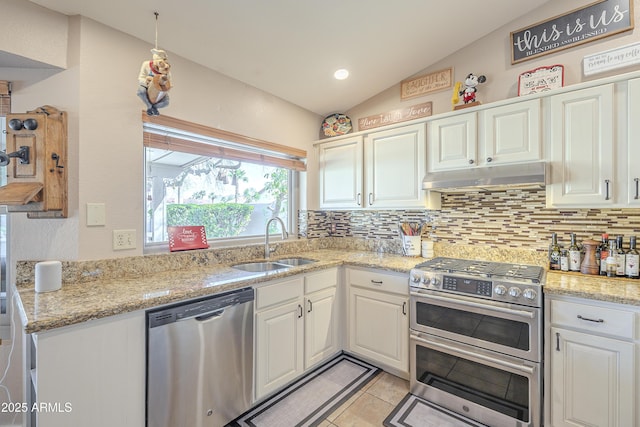 kitchen with under cabinet range hood, stainless steel appliances, a sink, vaulted ceiling, and backsplash