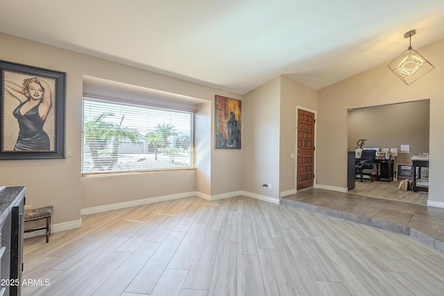 unfurnished living room featuring lofted ceiling, wood finished floors, and baseboards