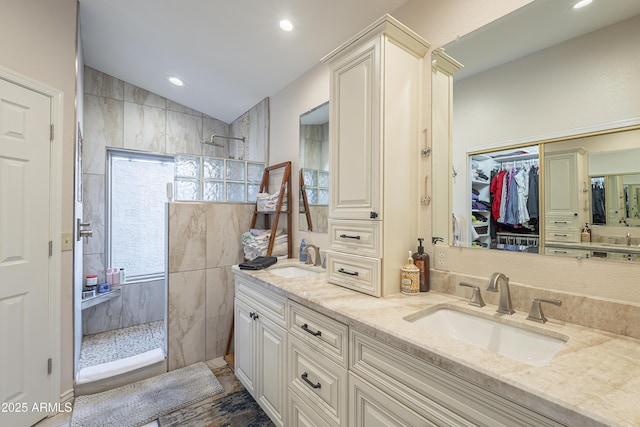 bathroom featuring double vanity, walk in shower, and a sink