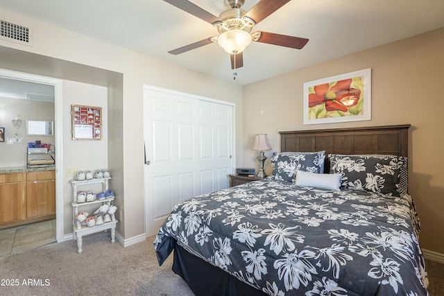 bedroom with baseboards, visible vents, a ceiling fan, light colored carpet, and a closet