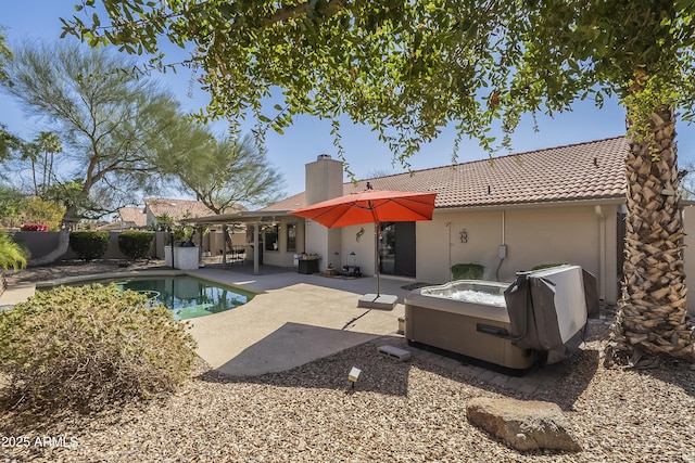 back of property with a fenced in pool, a chimney, a patio area, and a tiled roof