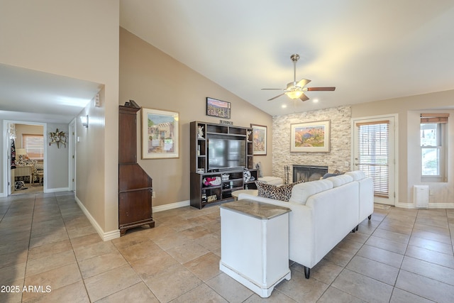 living area with a fireplace, light tile patterned floors, a ceiling fan, high vaulted ceiling, and baseboards