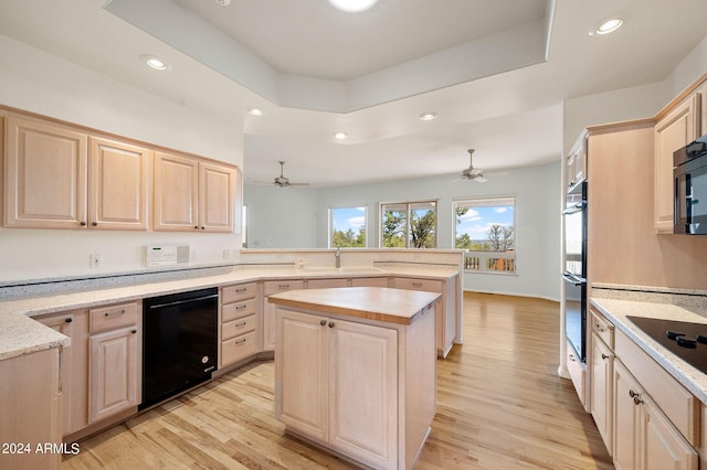 kitchen featuring black appliances, light hardwood / wood-style floors, a kitchen island, and light brown cabinetry