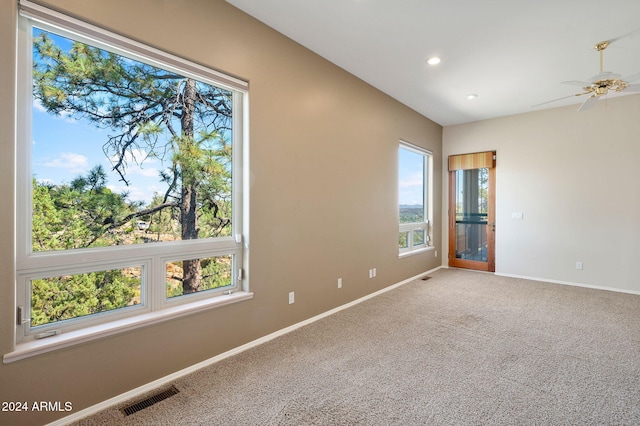 carpeted spare room with ceiling fan and plenty of natural light