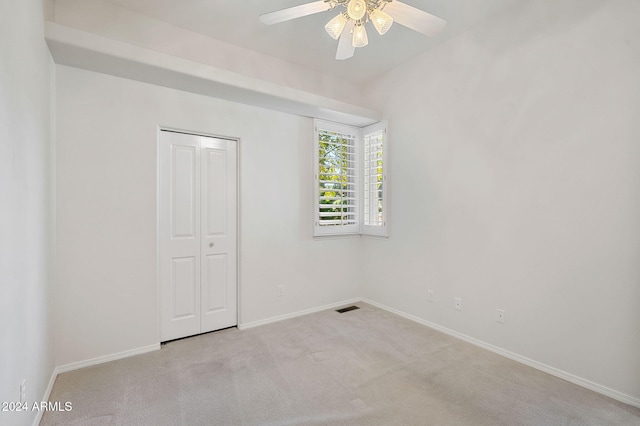 unfurnished bedroom featuring ceiling fan, light colored carpet, and a closet