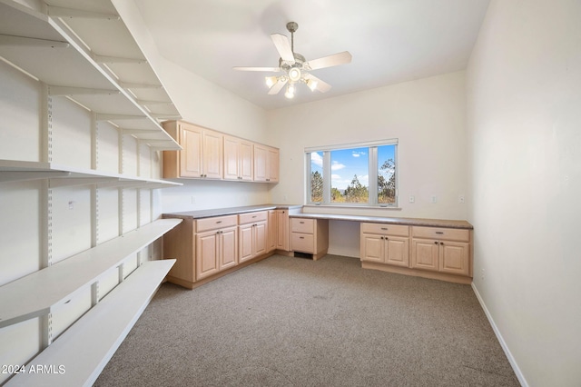 interior space featuring built in desk, ceiling fan, and light carpet