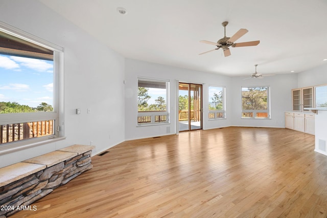 unfurnished living room featuring a wealth of natural light, ceiling fan, and light wood-type flooring