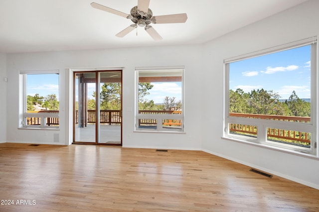 empty room featuring ceiling fan, light hardwood / wood-style flooring, and a healthy amount of sunlight