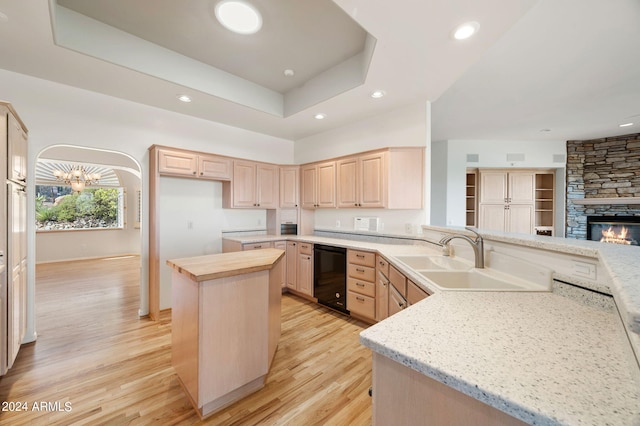 kitchen featuring dishwasher, light brown cabinets, light stone countertops, a center island, and light hardwood / wood-style flooring