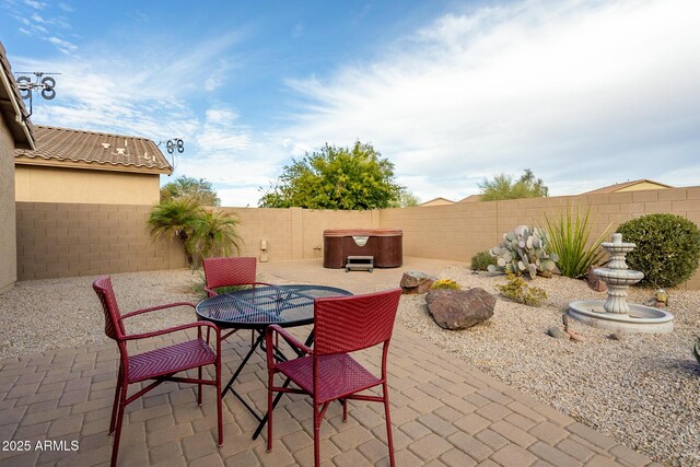 view of patio with a fenced backyard, outdoor dining area, and a hot tub