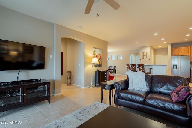 living room featuring light tile patterned floors, baseboards, arched walkways, a ceiling fan, and recessed lighting