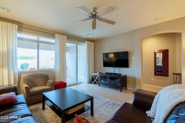 living area with visible vents, ceiling fan, arched walkways, and light tile patterned floors