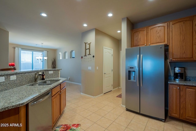 kitchen with light stone countertops, recessed lighting, a sink, stainless steel appliances, and brown cabinets