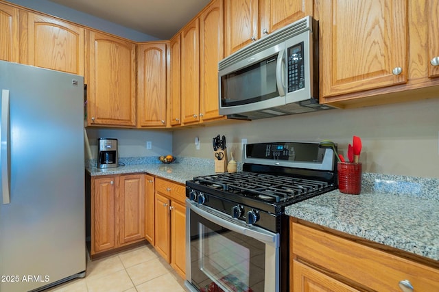 kitchen featuring light stone countertops, light tile patterned flooring, and stainless steel appliances