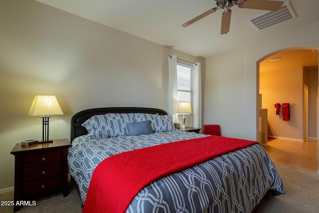 carpeted bedroom featuring visible vents, baseboards, a ceiling fan, and arched walkways