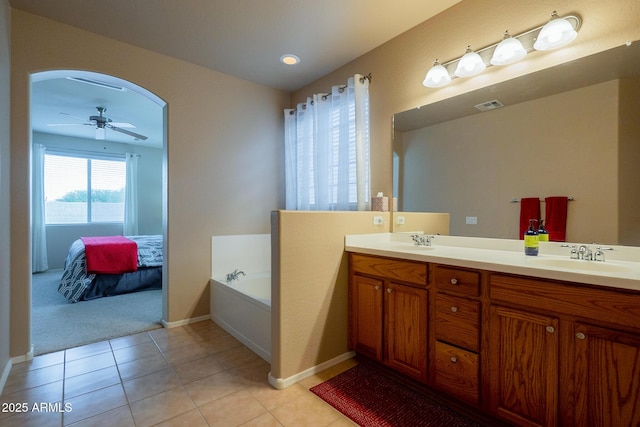 ensuite bathroom with ceiling fan, tile patterned floors, double vanity, and a sink