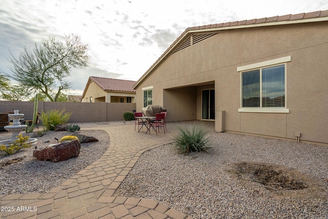 rear view of house with a patio, stucco siding, fence, and a tile roof
