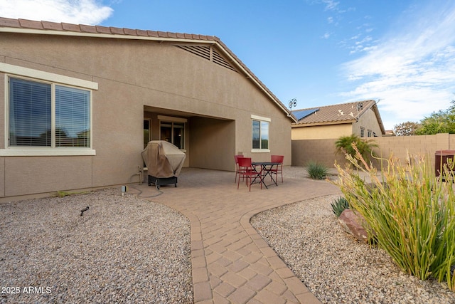 rear view of house featuring a patio area, stucco siding, and fence