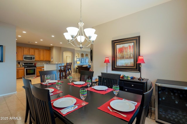 dining area featuring light tile patterned floors, arched walkways, an inviting chandelier, recessed lighting, and beverage cooler