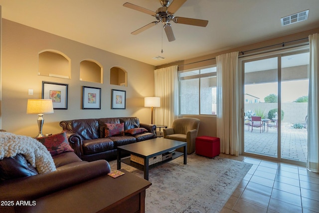 living area featuring tile patterned floors, visible vents, and ceiling fan