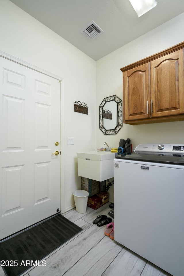 laundry room featuring cabinets, washing machine and clothes dryer, and light wood-type flooring