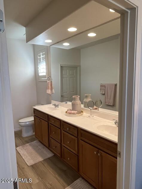 bathroom with toilet, hardwood / wood-style flooring, and vanity