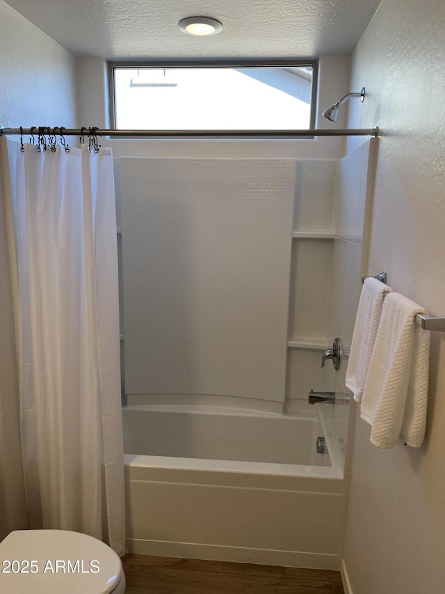 bathroom featuring a healthy amount of sunlight, shower / tub combo with curtain, and a textured ceiling