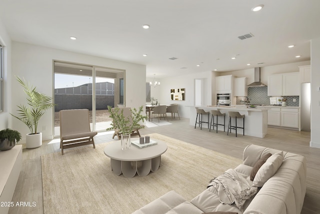 living room with light wood-type flooring and an inviting chandelier