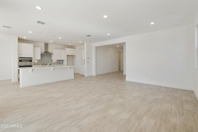 unfurnished living room with light hardwood / wood-style flooring and sink