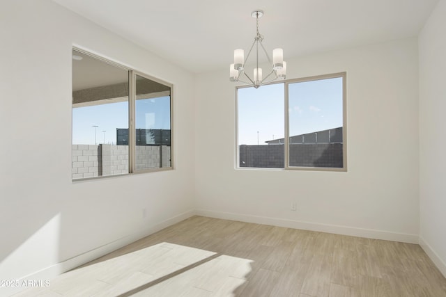 spare room with light hardwood / wood-style flooring and an inviting chandelier