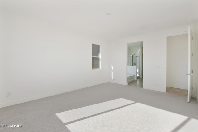 unfurnished bedroom featuring light carpet and ensuite bath