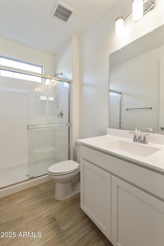 bathroom featuring hardwood / wood-style floors, an enclosed shower, and toilet