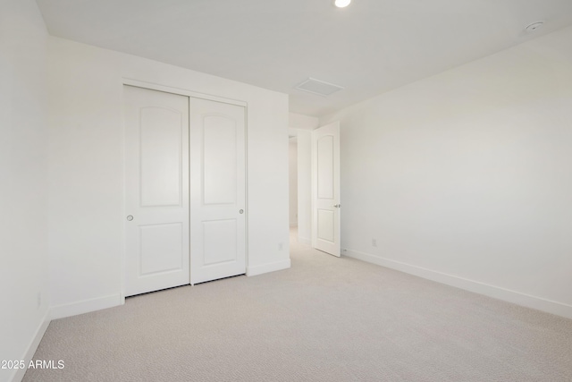 unfurnished bedroom with a closet and light colored carpet