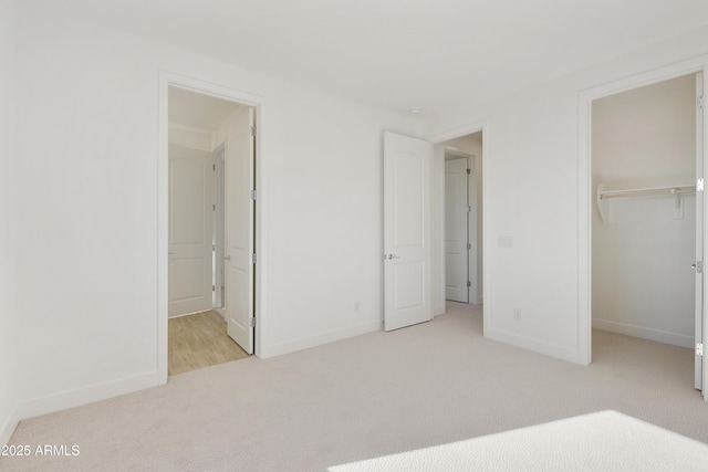 unfurnished bedroom featuring ensuite bathroom, a spacious closet, light carpet, and a closet