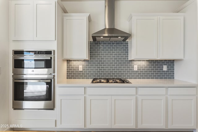 kitchen with white cabinets, decorative backsplash, stainless steel appliances, and wall chimney exhaust hood