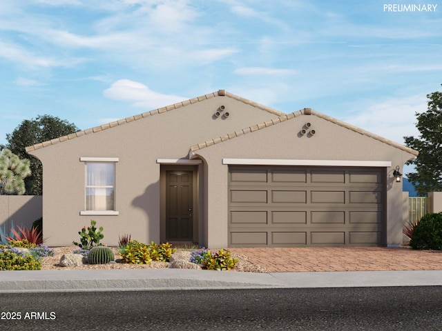 mediterranean / spanish home featuring a garage, decorative driveway, fence, and stucco siding