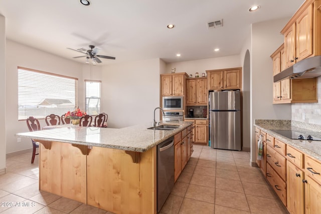 kitchen with backsplash, a kitchen breakfast bar, sink, an island with sink, and appliances with stainless steel finishes