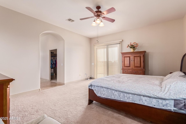 bedroom featuring ceiling fan, light colored carpet, and a spacious closet