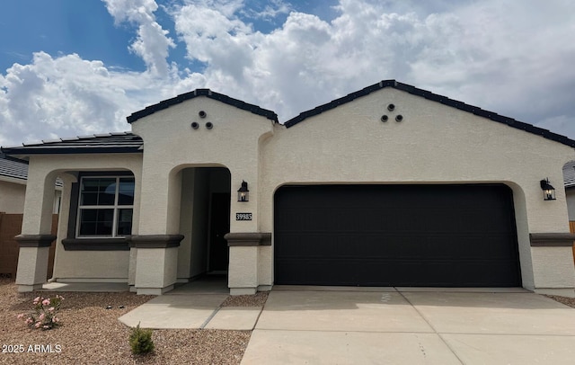 mediterranean / spanish-style house with an attached garage, stucco siding, concrete driveway, and a tile roof