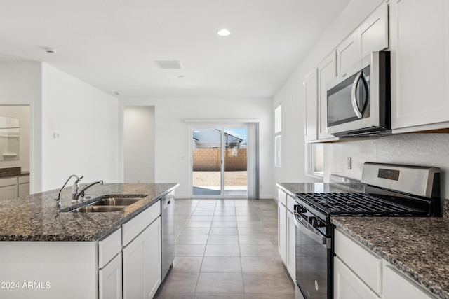 kitchen featuring appliances with stainless steel finishes, a sink, dark stone counters, white cabinetry, and recessed lighting