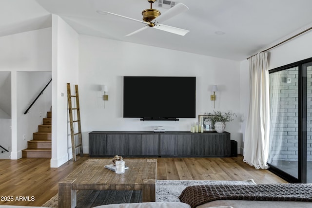 living area with lofted ceiling, stairway, ceiling fan, visible vents, and wood finished floors