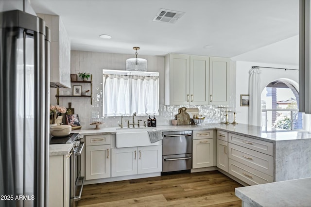 kitchen with a healthy amount of sunlight, appliances with stainless steel finishes, a sink, visible vents, and a peninsula