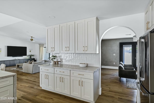 kitchen featuring dark wood-style flooring, ceiling fan, arched walkways, freestanding refrigerator, and open floor plan
